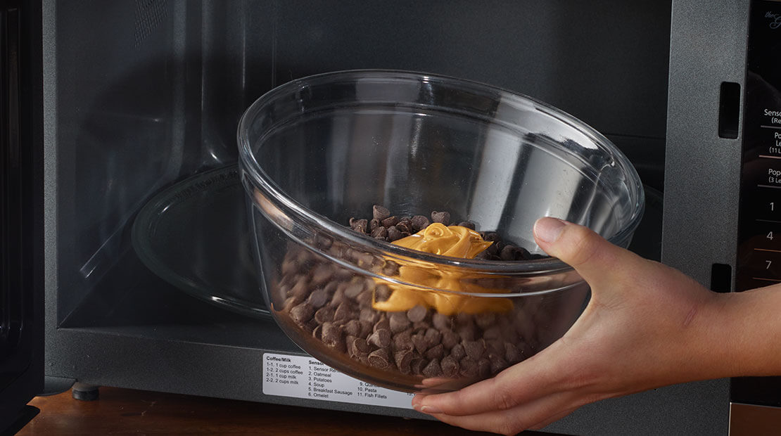 bowl of peanut butter and chocolate chips in a microwave