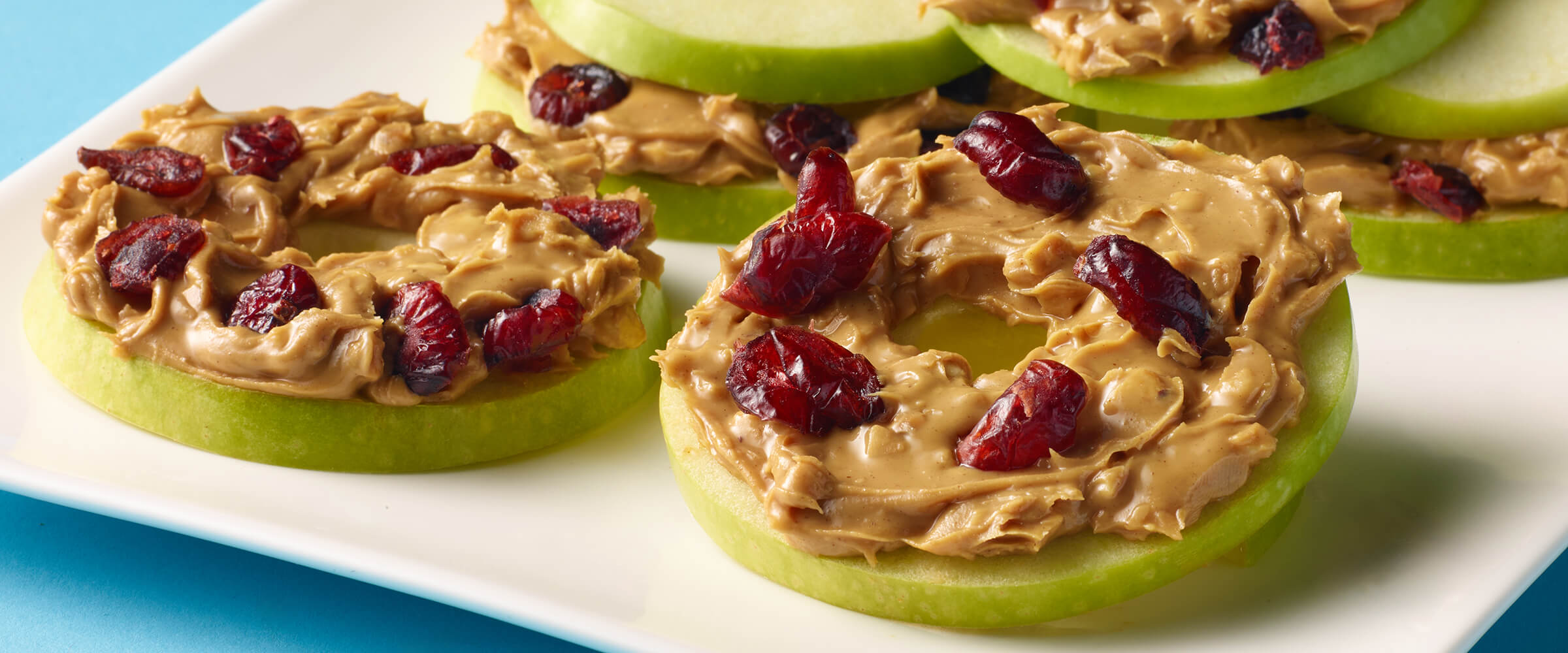 Apple Bagel Snacks on a white plate, covered in peanut butter and raisins
