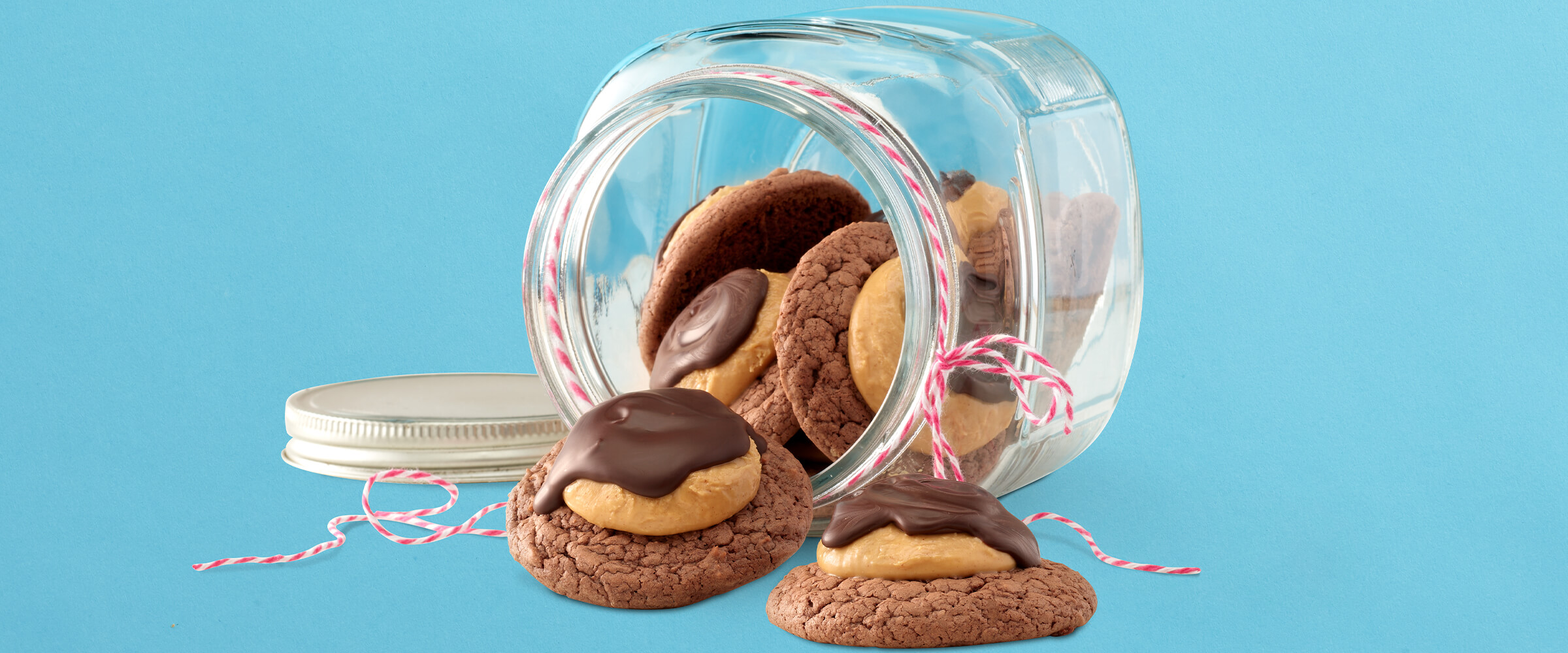 Buckeye brownie cookies spilling out of a large jar with red and white twine tied around the top.
