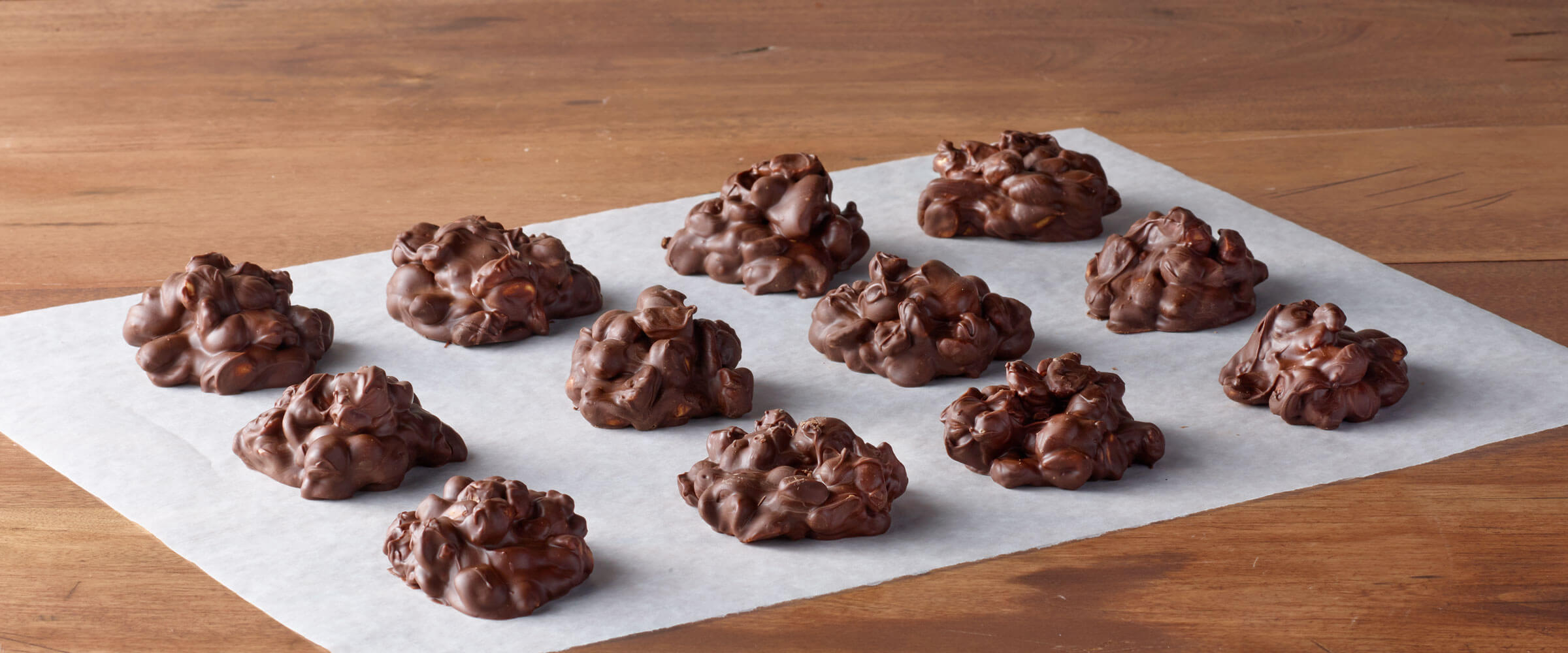 Chocolate candies on parchment paper, sitting on a wooden table