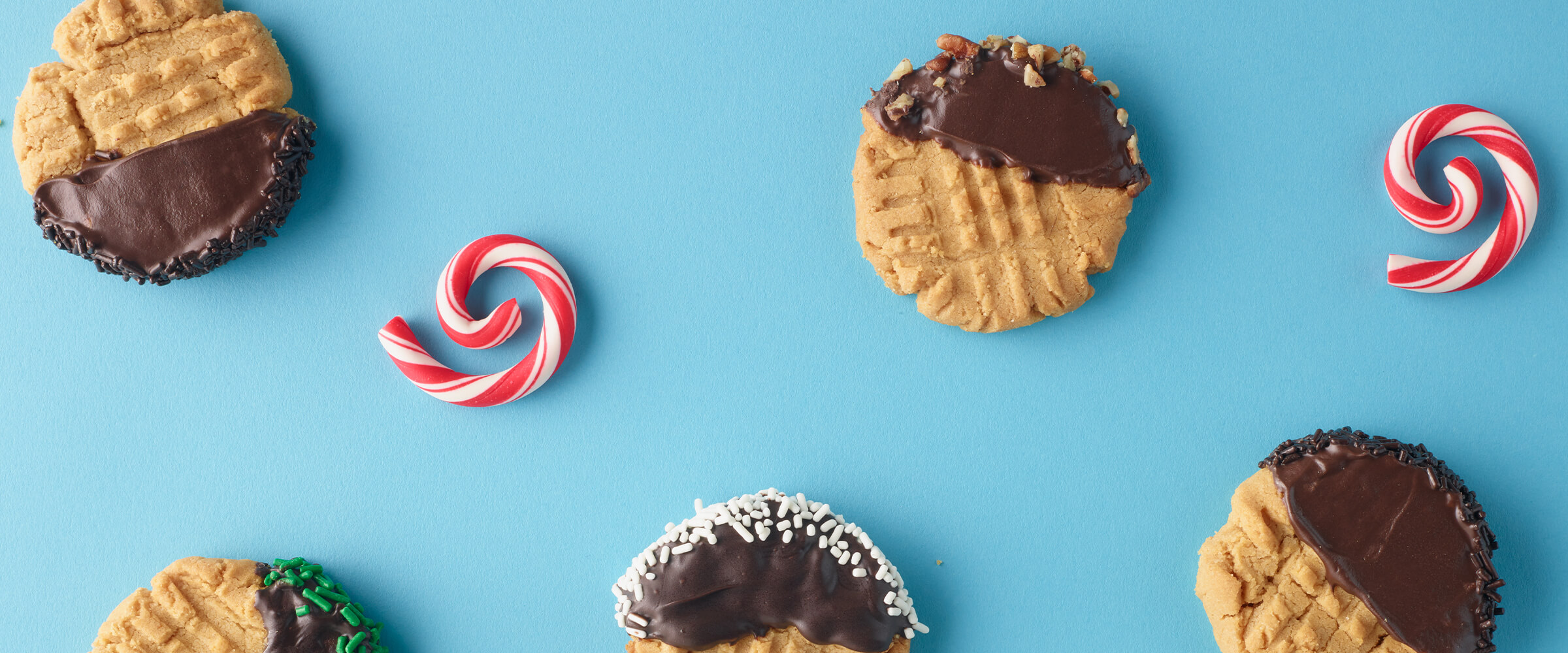 Chocolate dipped peanut butter cookies on a teal background with peppermint swirls