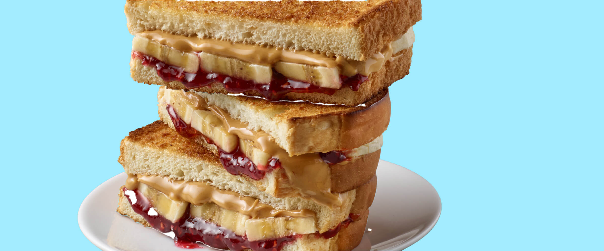 Three grilled and stuffed sandwiches stacked on top of each other on a white plate with a teal background.