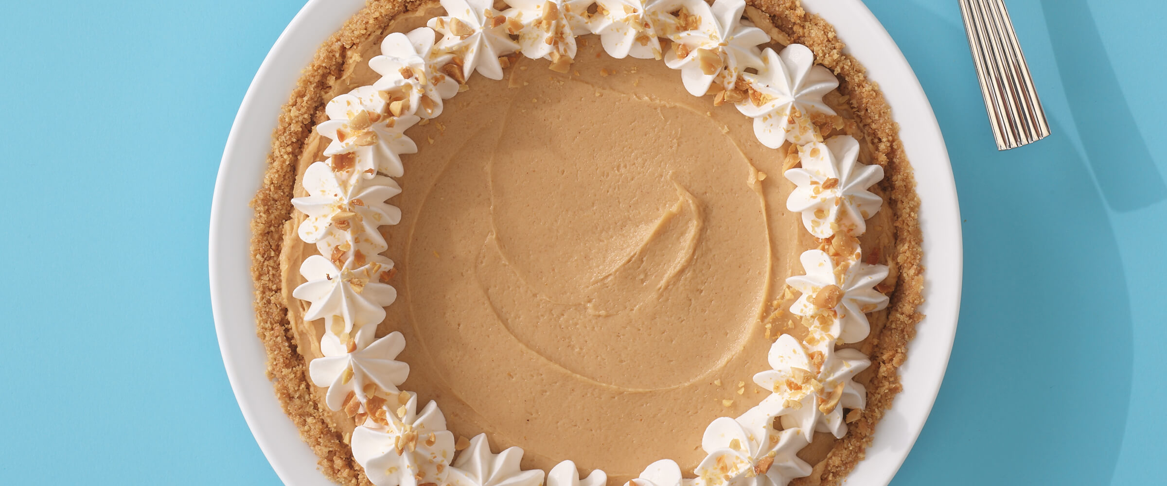 No-bake peanut butter cheesecake in a white serving dish on a teal background.