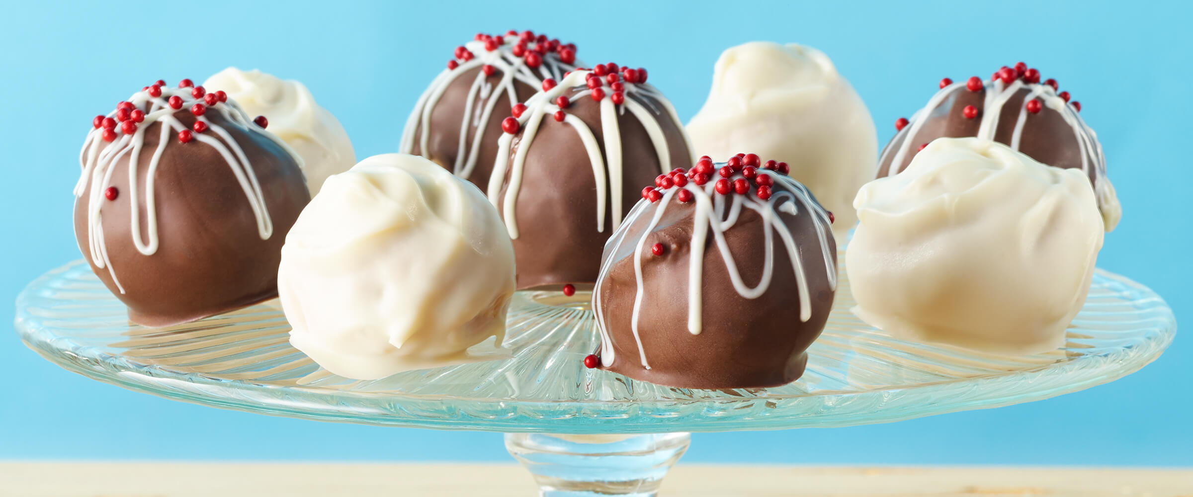 Eight no bake peanut butter crunch balls on a glass cake stand.