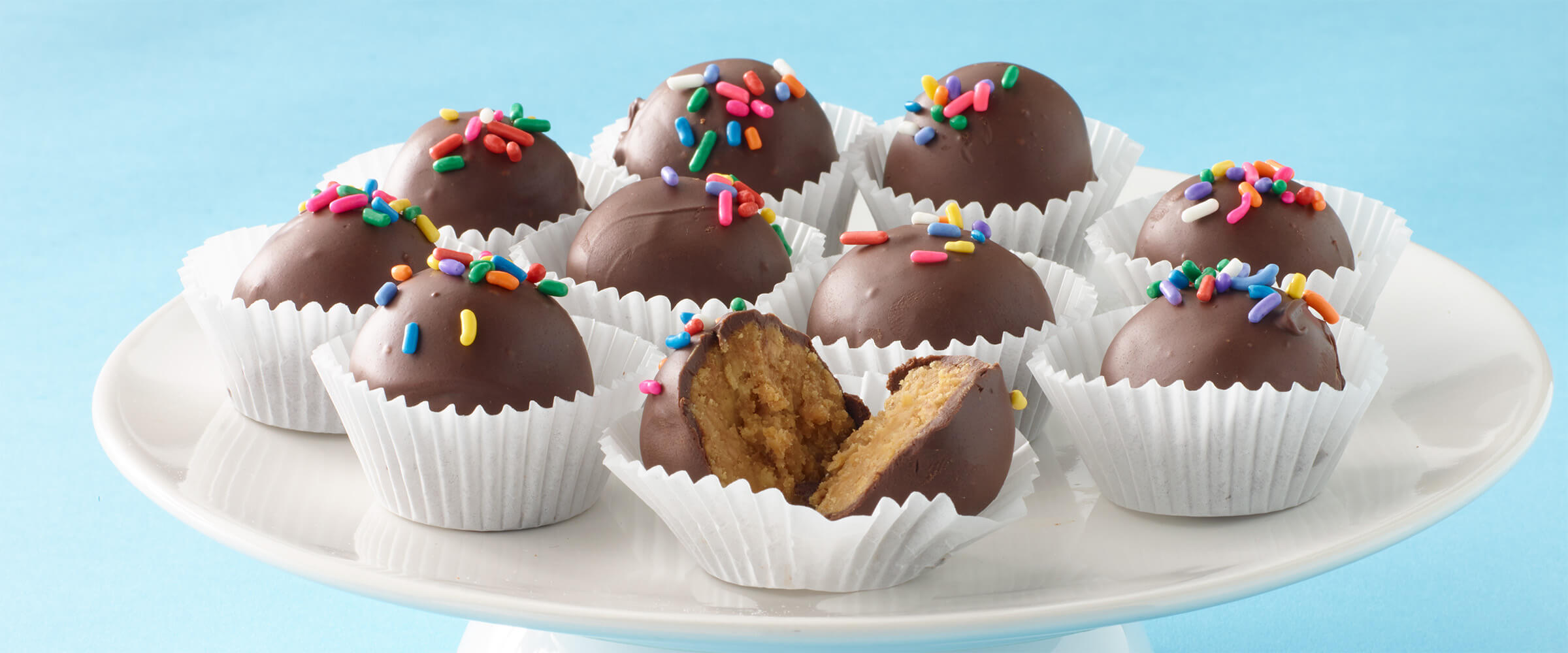 peanut butter truffles in individual wrappers, the front split in half to view the cheesecake filling