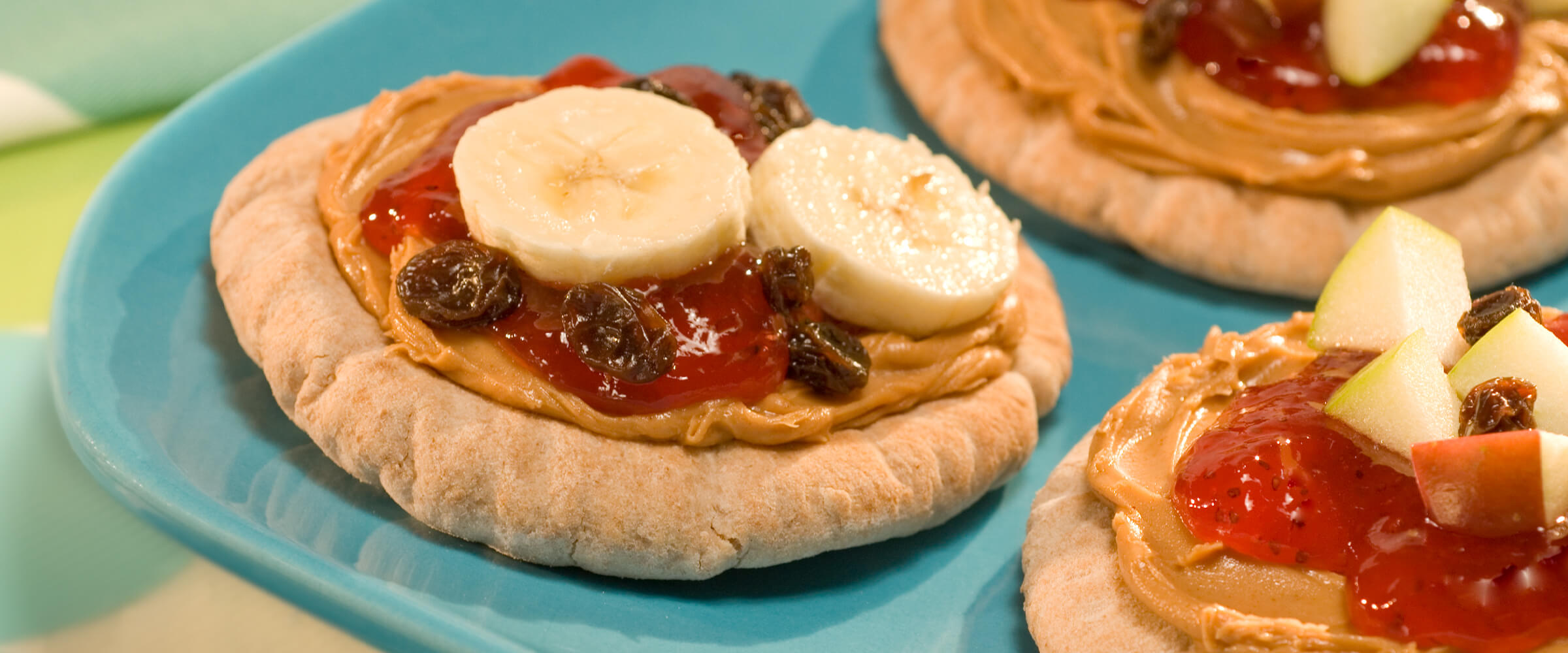 Three peanut butter and jelly pitas on a teal plate.