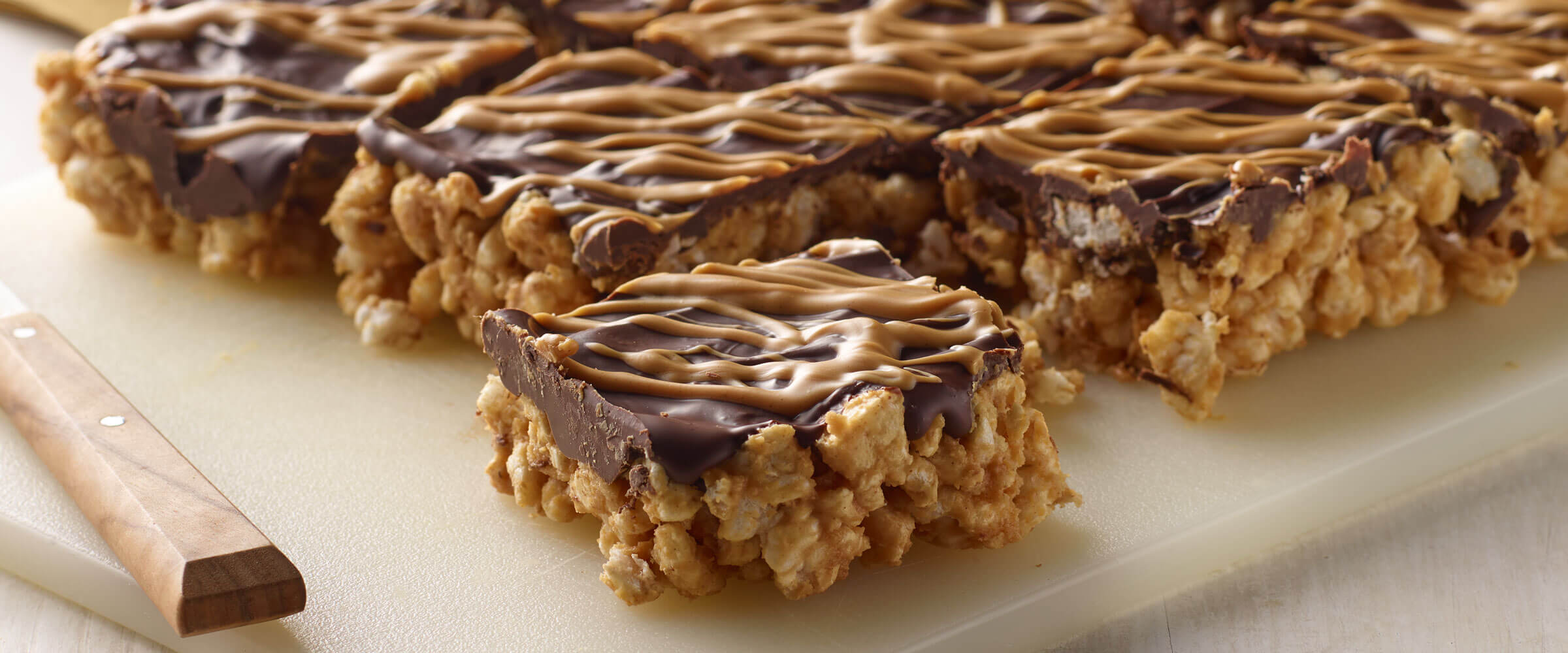 Peanut Butter Chocolate Rice Cake Bars on a cutting board with a knife