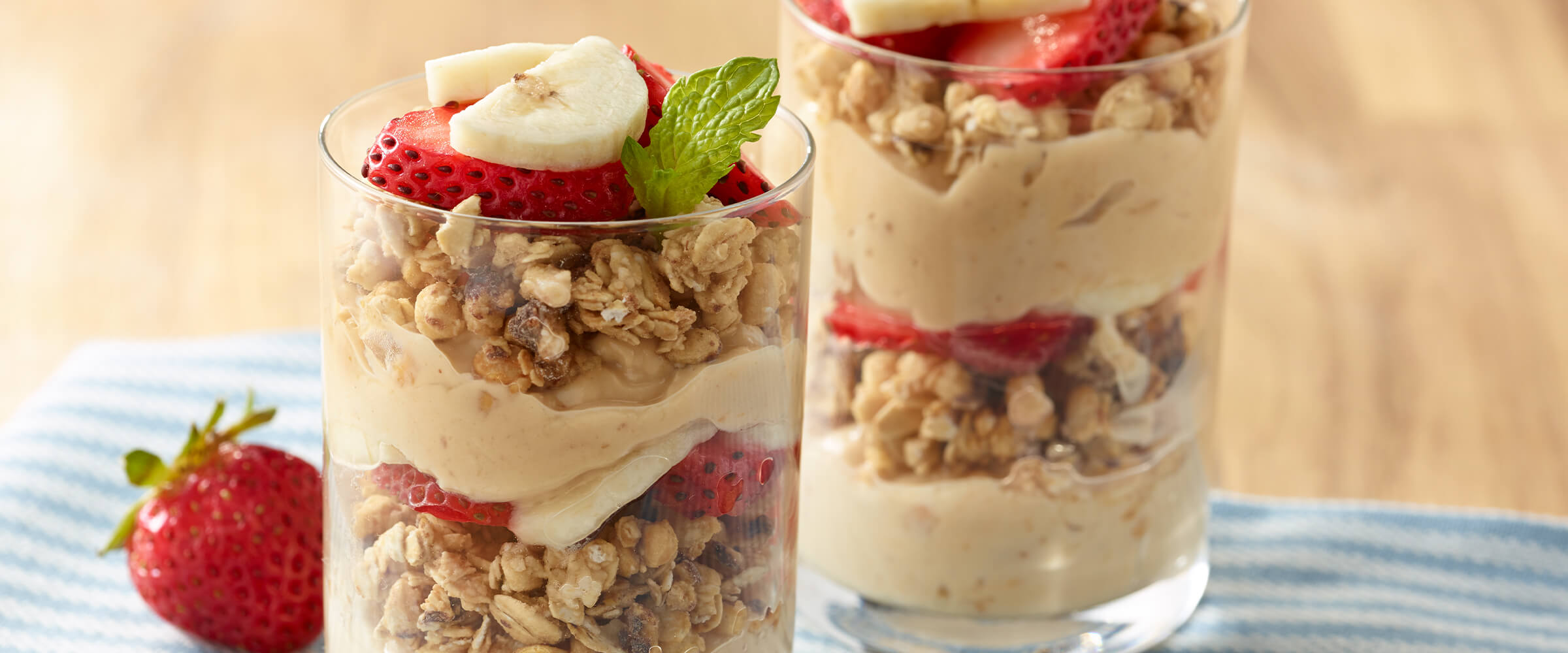 Two peanut butter parfaits sitting on a teal and white towel.