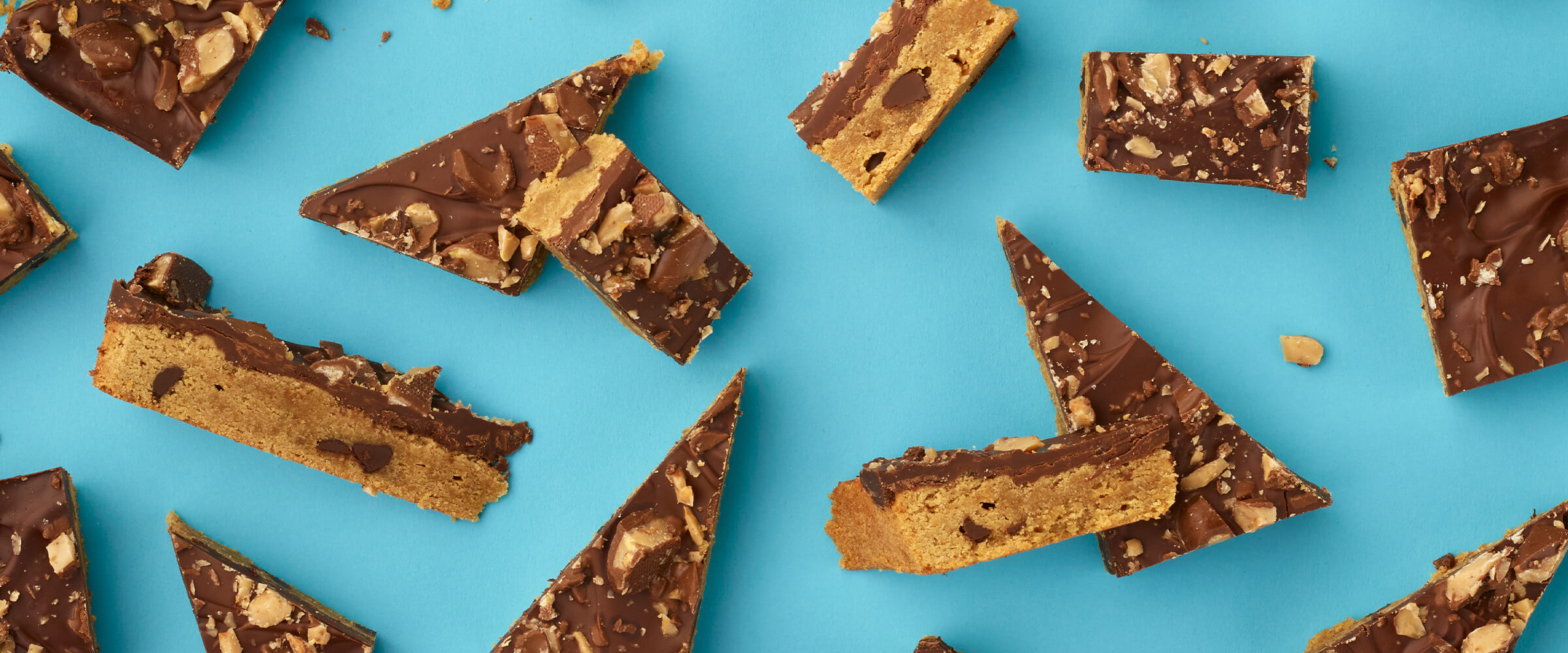 Pieces of peanut butter toffee bar sitting on a teal background.