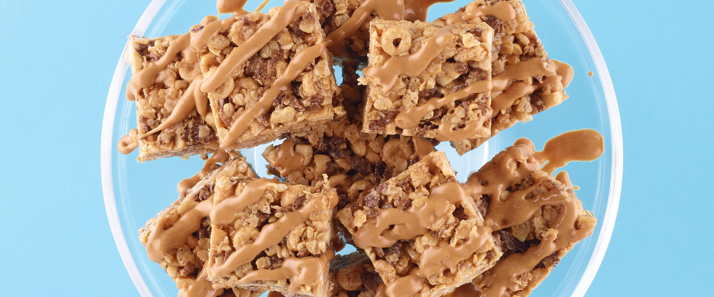 Peanut butter and oatmeal cereal bars drizzled with melted peanut butter and a glass serving dish.