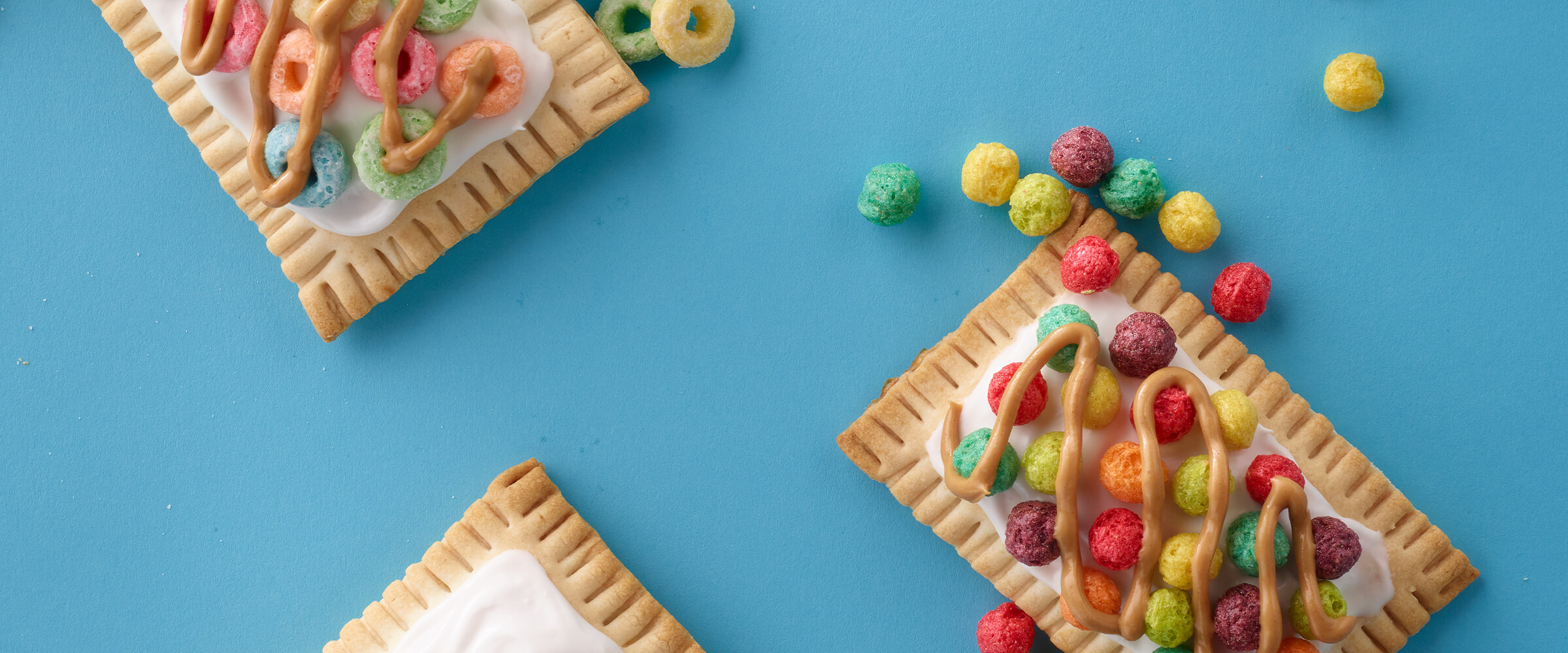 Three peanut butter pajama jammers with colorful cereal on top, spilling onto the teal background.