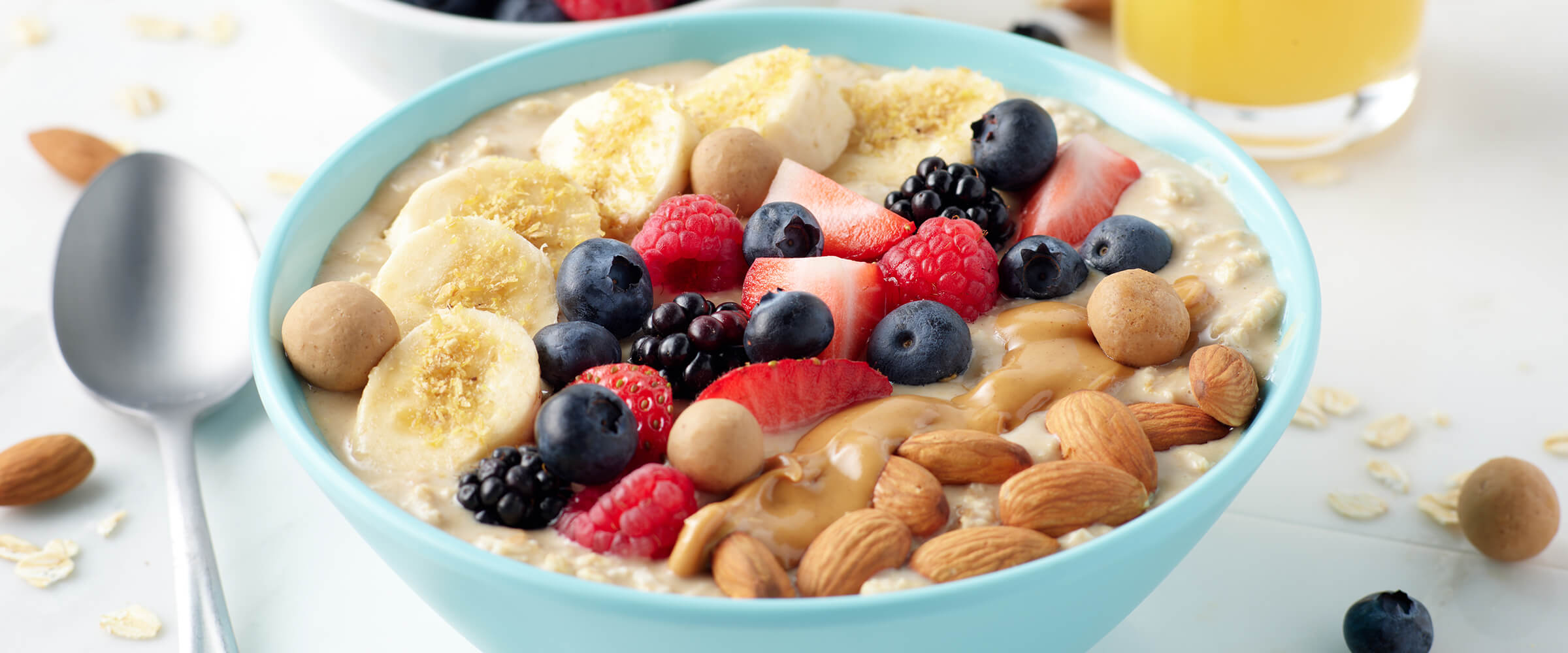 Overnight peanut butter oats topped with bananas, berries, almonds in a light blue bowl