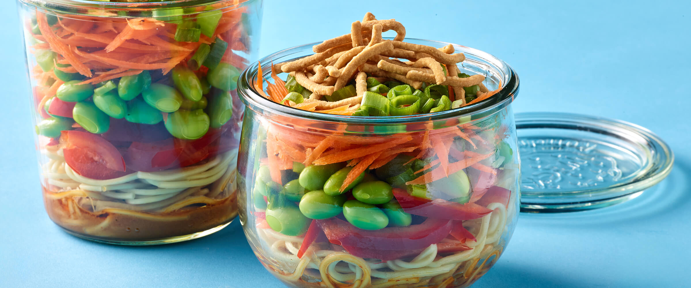 Glass container with layers of vegetables and noodles