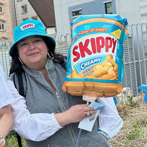 Woman wearing a skippy branded bucket hat and holding a skippy jar balloon.