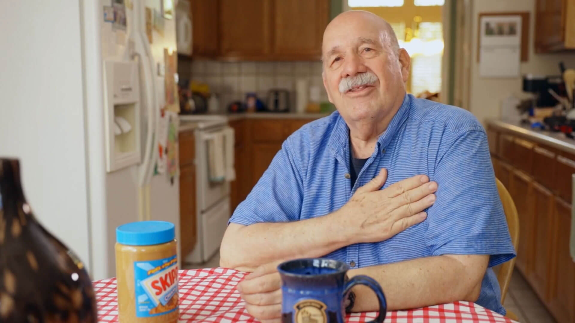 Joe Milligan at his kitchen table with a jar of skippy creamy peanut butter