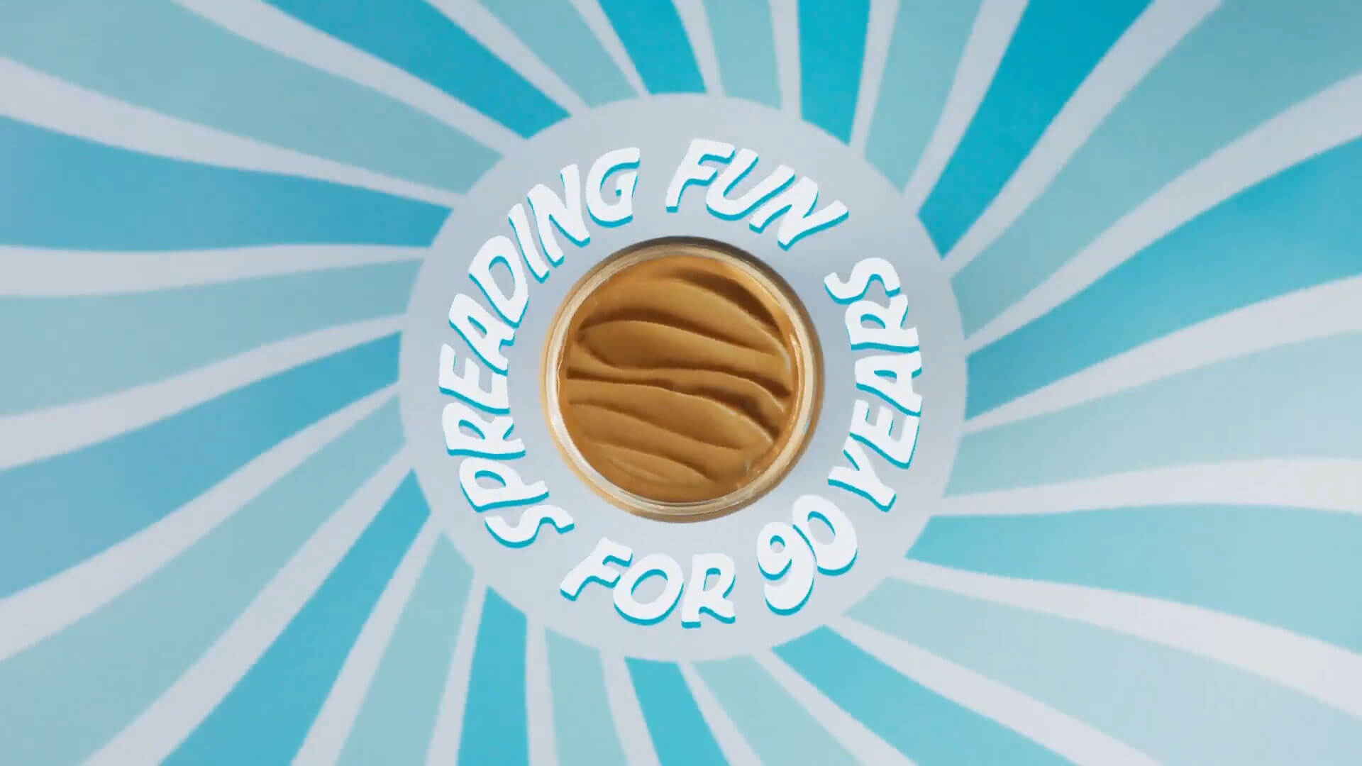 an overhead view of a jar of peanut butter with the words spreading fun for 90 years around it